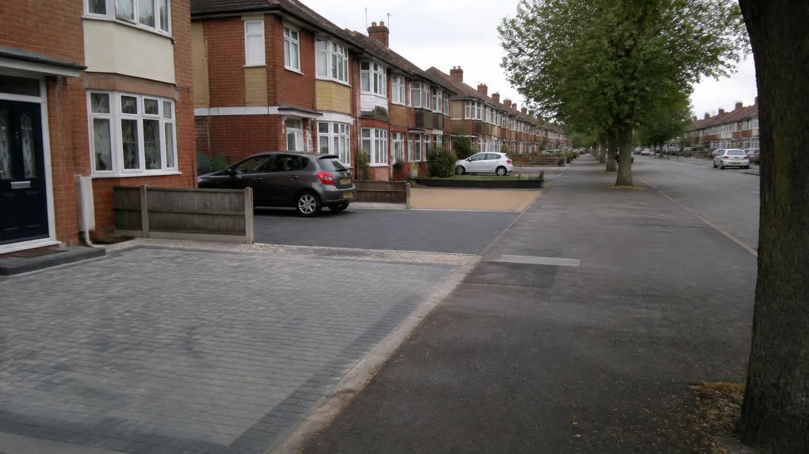 Residential street of brick semis with a mix of driveway surfaces