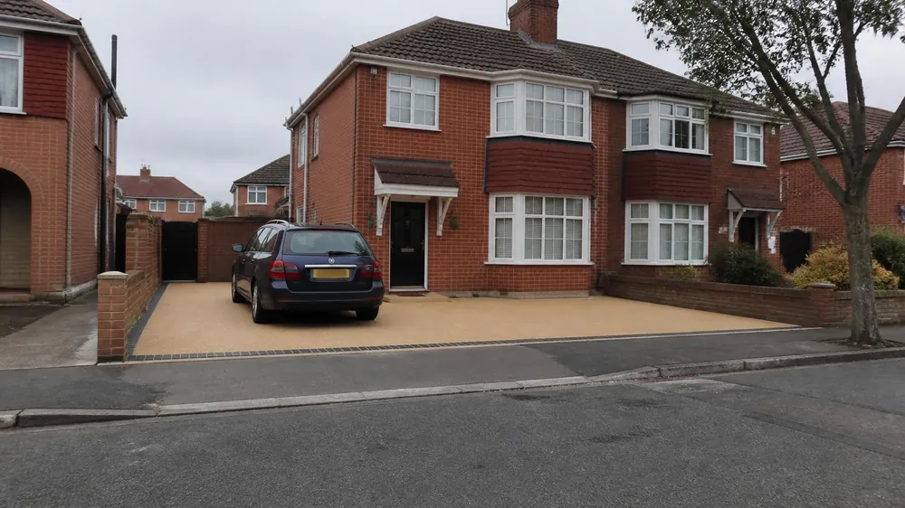 Red-brick bay-fronted semi with a new block-paved driveway leading to the front door