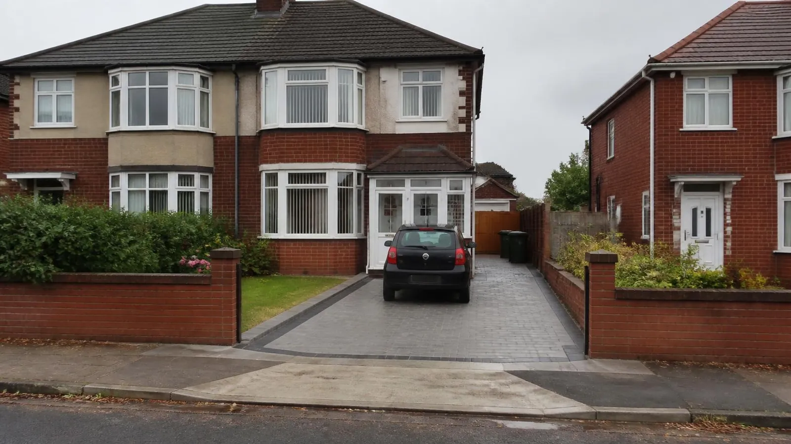Dropped kerb crossing leading onto a block-paved driveway outside a 1930s semi