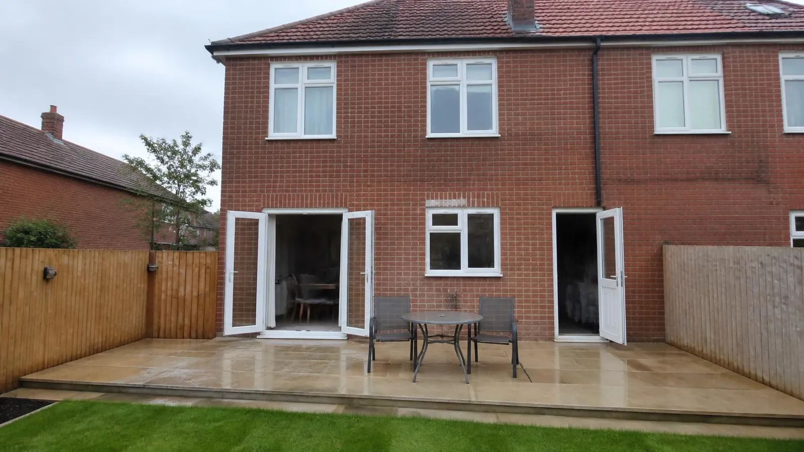 Sandstone patio laid against the back of a brick house