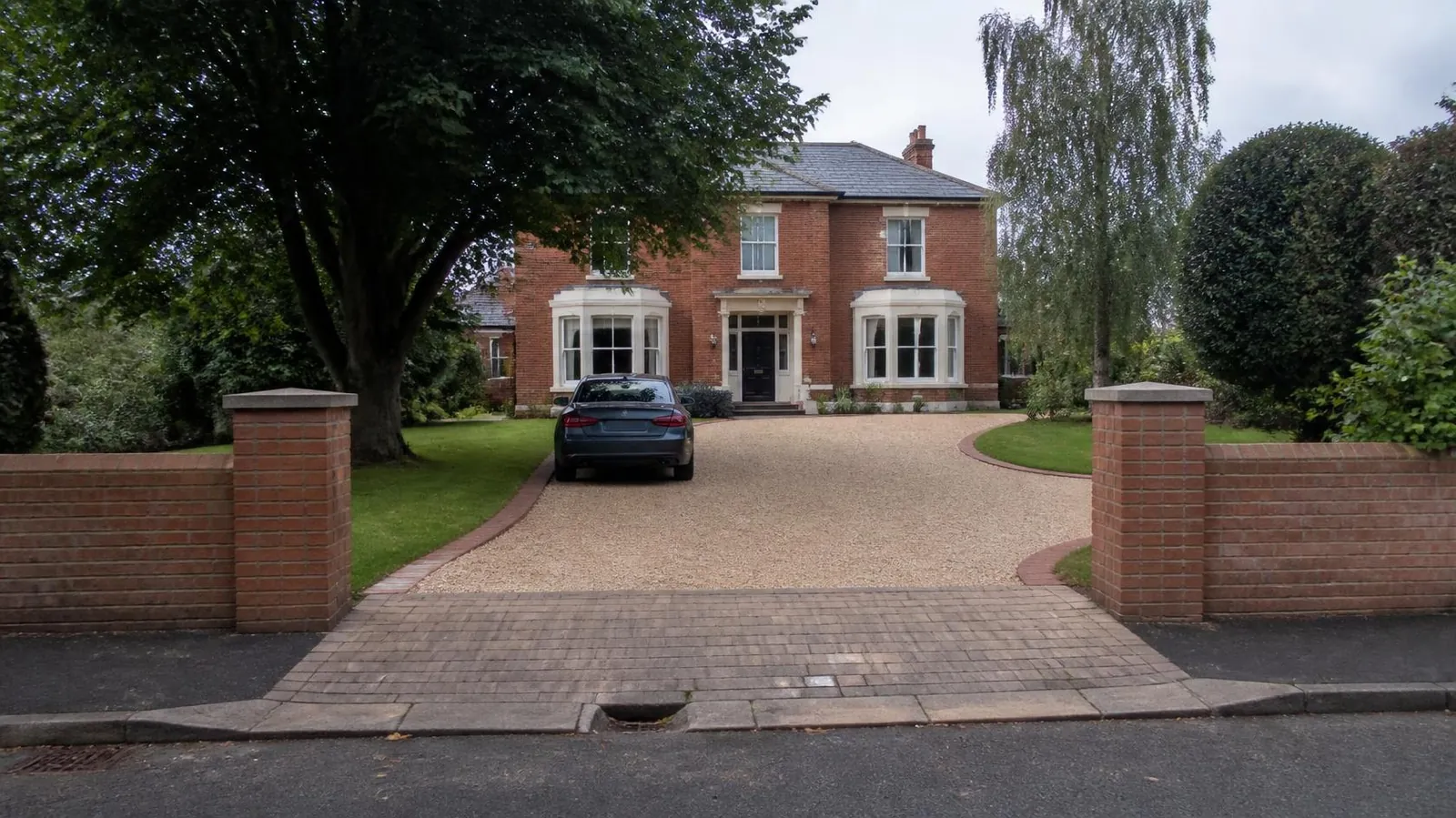 Edwardian villa with a gravel driveway between brick gate piers