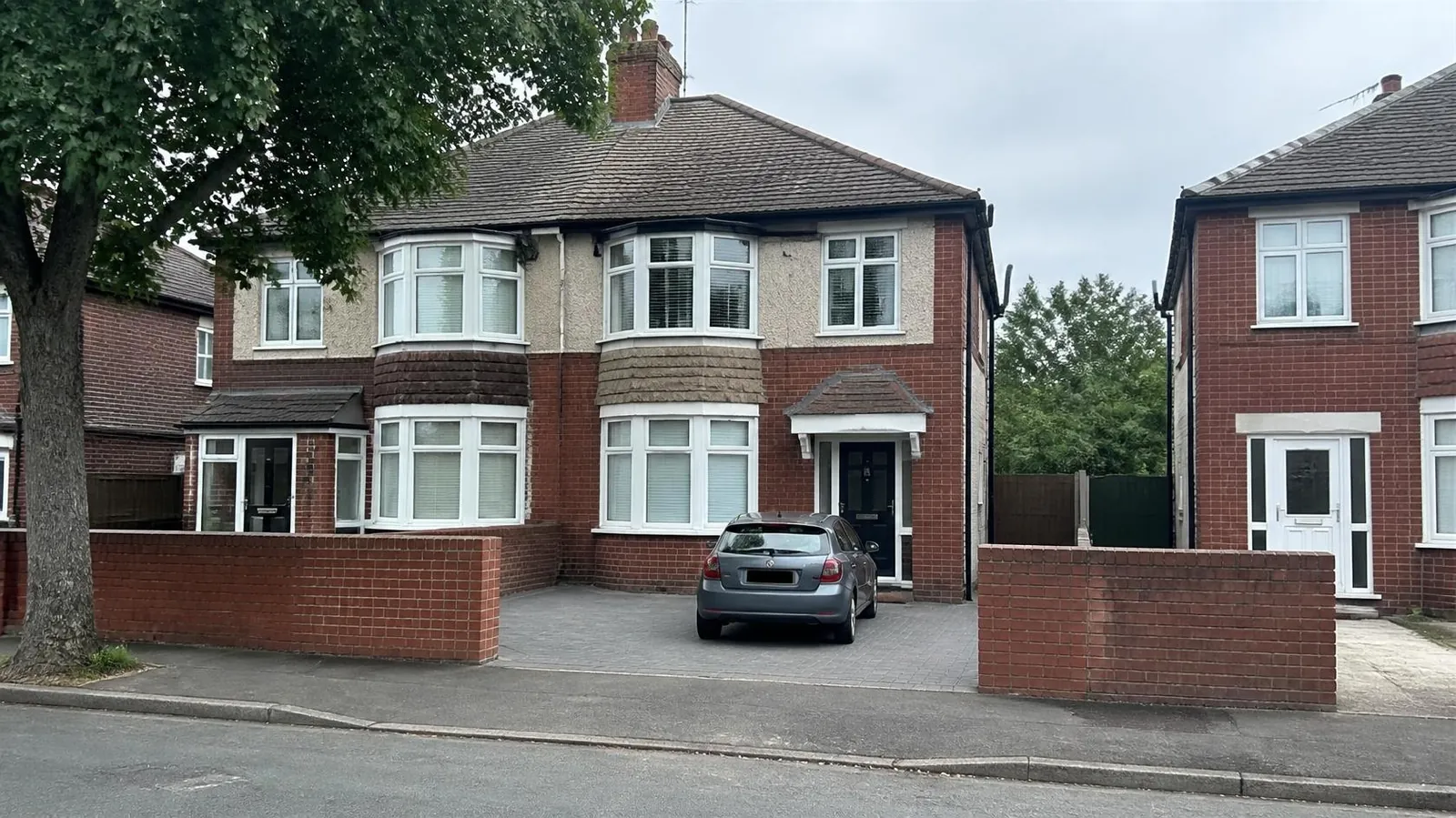 Inter-war bay-fronted semi with a block-paved drive behind a low brick wall